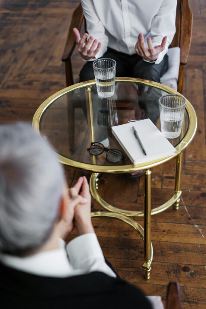 pexels photo 4098369 4098369 Two adults discussing mental health in a counseling session across a glass table indoors.